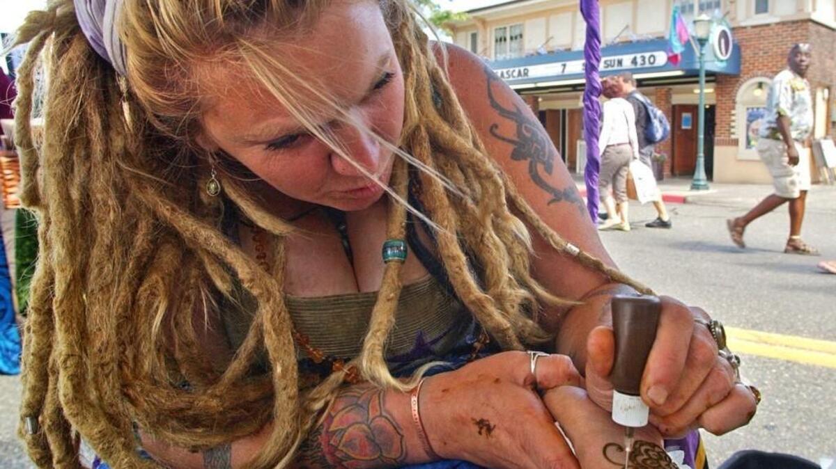 Dagmar Peterson appies henna to decorate a teen’s arm in her booth at the 2005 Proctor District Arts Festival.