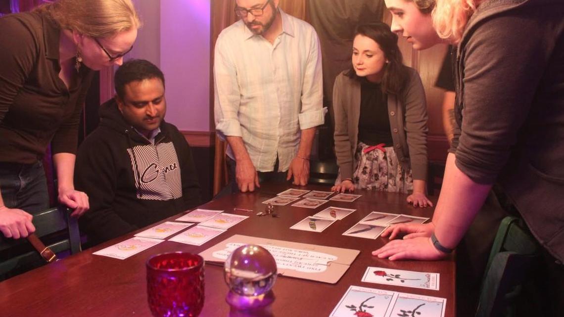 A group pores over mysterious tarot cards, one of the many puzzles in “The Last Escape” room.