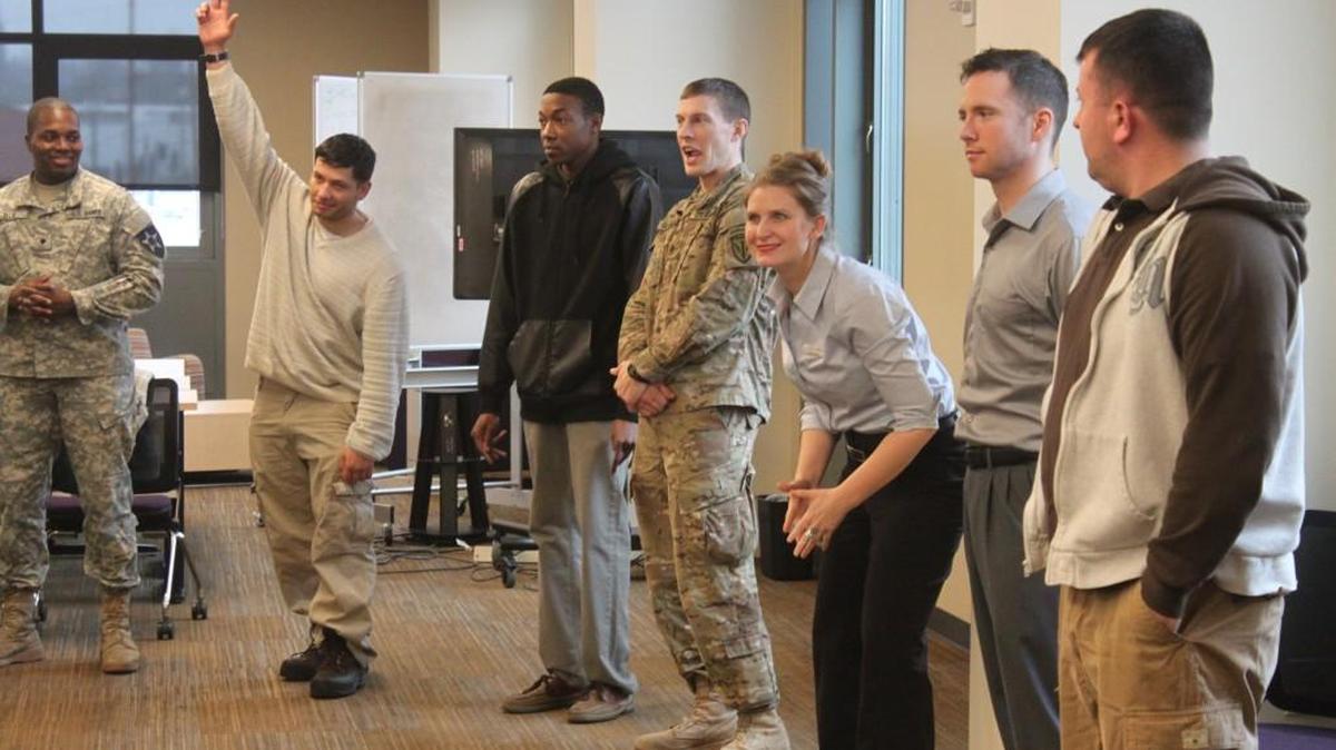 Participants in a Yes Works improv workshop for transitioning military play a circle memory game. Yes Works member Rachel Lionheart (center) helps things along.