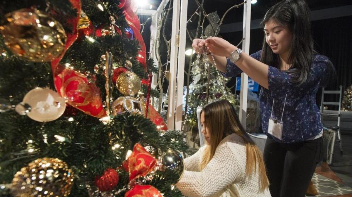 Sharon Harrah, left, and April Lai hang decorations on tree for the display “Holiday at Home” for the Festival of Trees, Mary Bridge Children’s Hospital’s annual holiday fundraiser in 2015. This year’s event is this weekend.