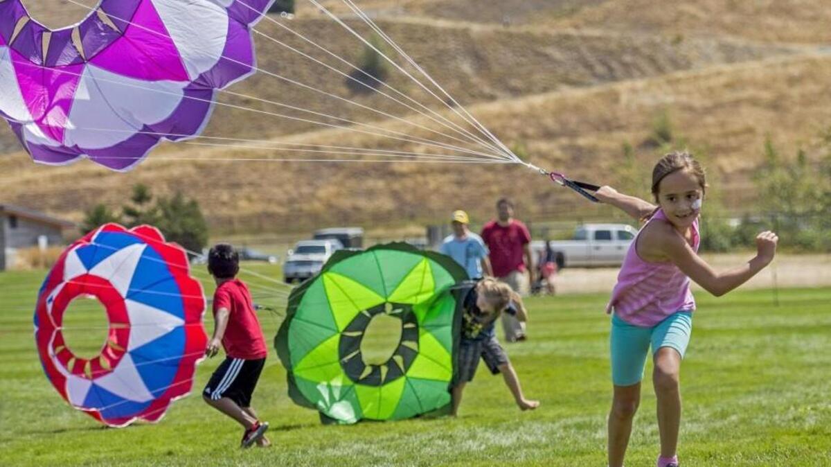 Leonna Young, 7, of Tacoma, tows a parachute across the finish line in Running of the Bulls during the Kite Festival in the central meadow at Chambers Creek Regional Park in 2014.