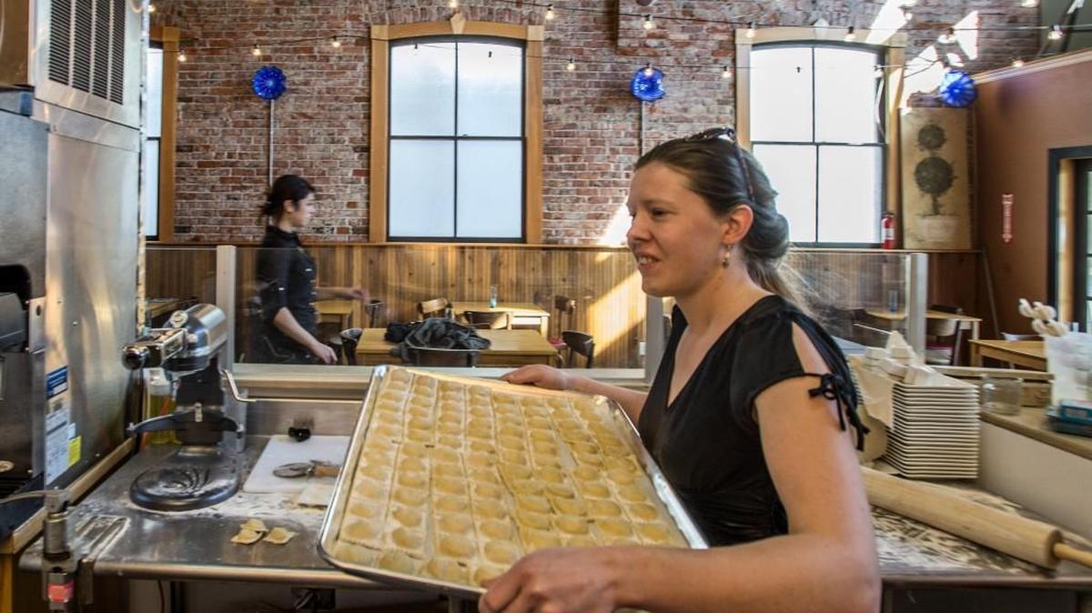 Margaret Herreid, sister of co-owner Ben Herreid, carries a tray of freshly-made chicken marsala ravioli at Arista in Puyallup.