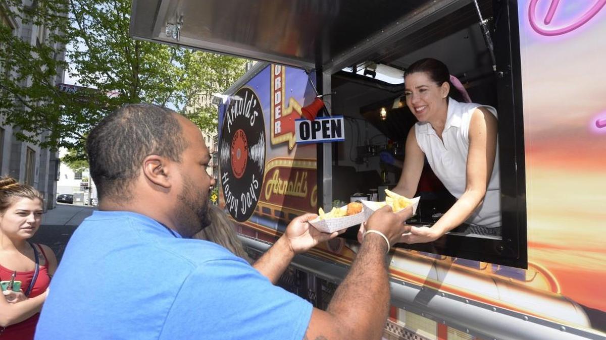 Donna Arnold, co-owner of Arnold’s Happy Days food truck, gives R.C. Campbell his order near the close of a first-ever food truck get-together on Market Street in Tacoma in 2015. The truck will serve this weekend at the Mobile Food Fest at Sprinker Recreation Center.