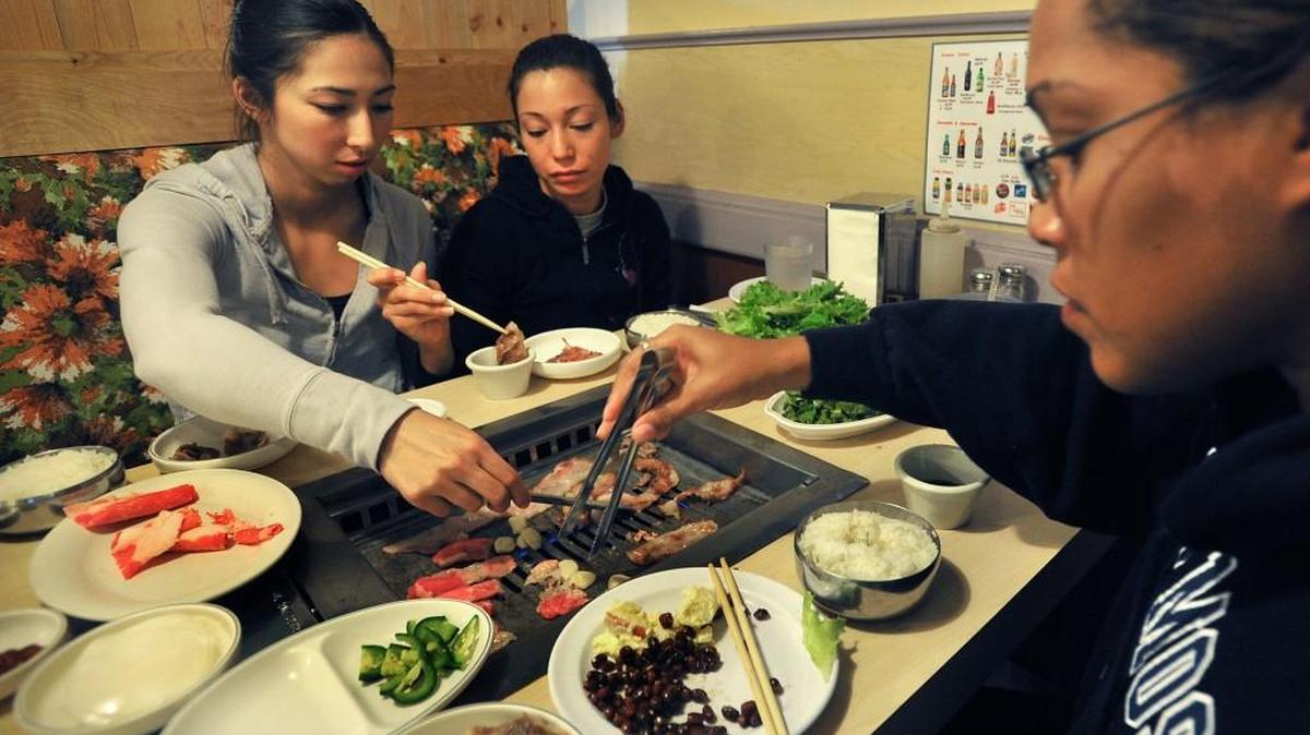 Jennifer Jones, left, Jesenia Fonseca, center, and Erica Rembert enjoy grilling the meat at their table at Cham Garden Korean BBQ in Lakewood.
