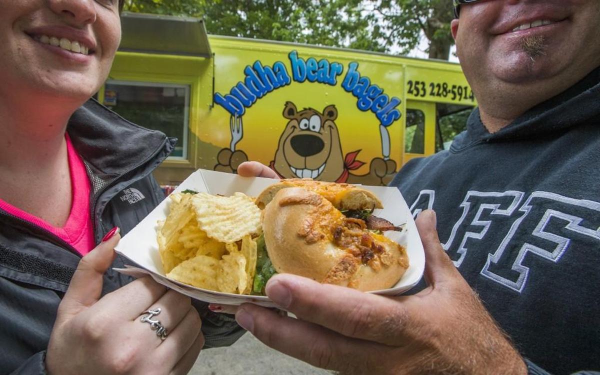 Ande Dunn and Darrin Shaw were happy to split a Bad Ass Burger from Buddha Bear Bagels at Food Truck Fest in Tacoma’s Wright Park, July 20, 2014. The truck will appear at food-truck festivals this summer.