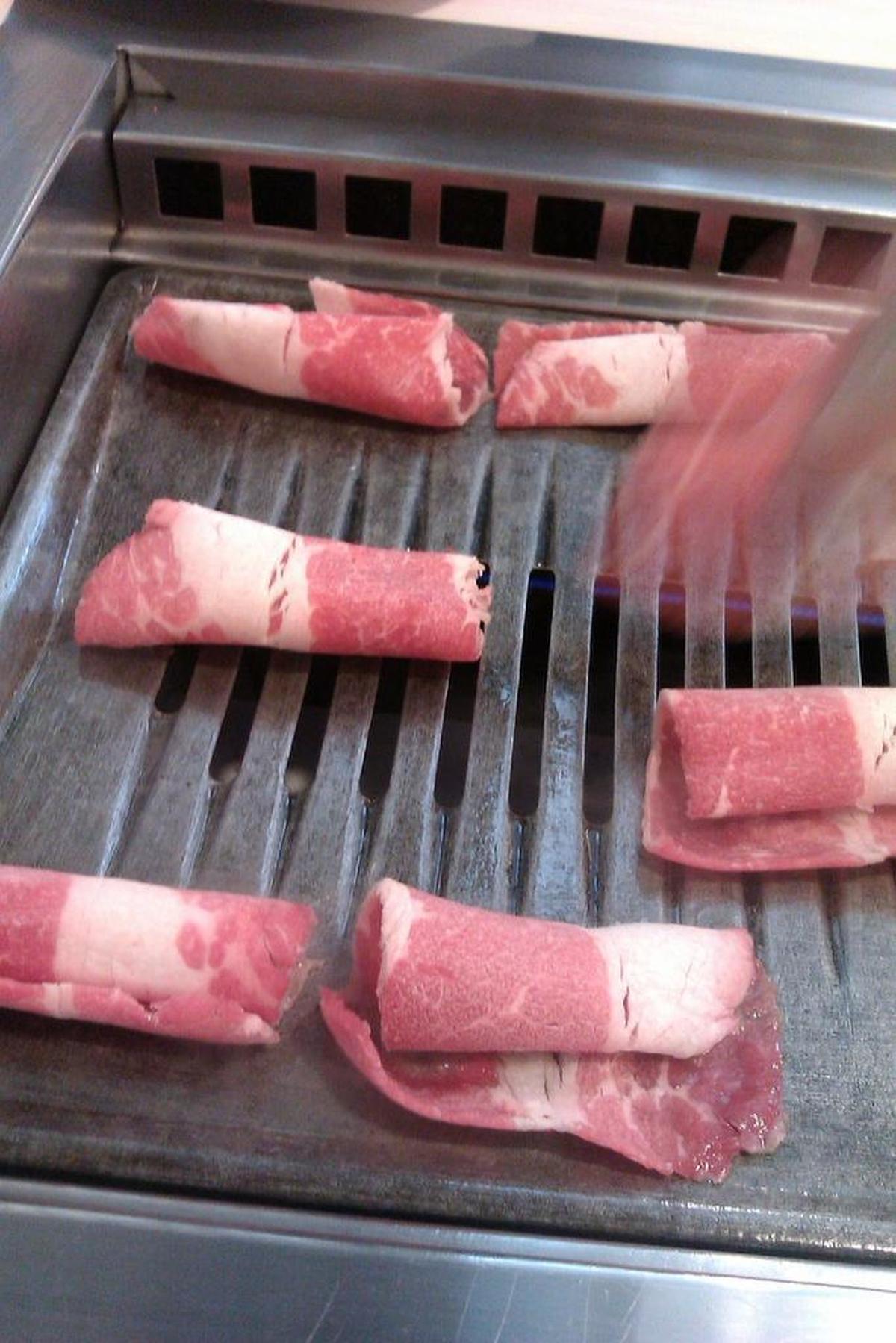 Diners grill their own meat on a tabletop barbecue at Cham Garden Korean BBQ.