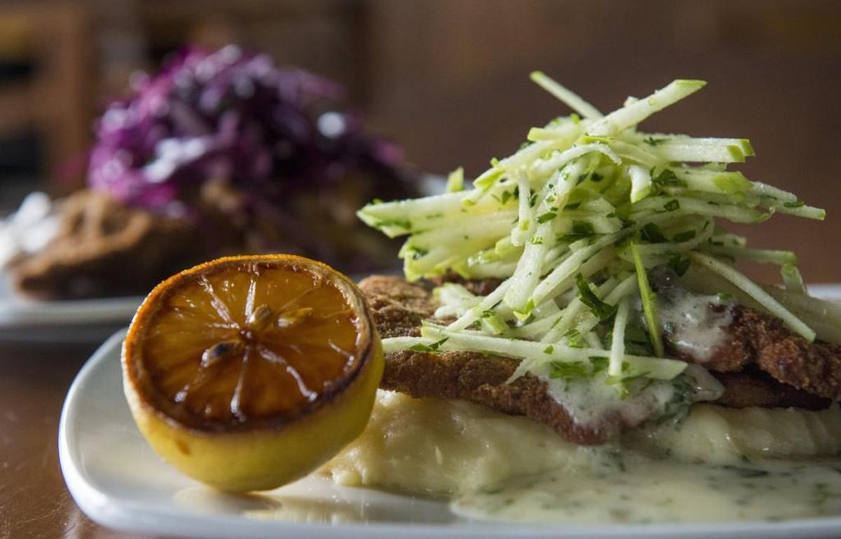 The pork schnitzel, front, comes with a green apple slaw, caper butter sauce and a caramelized lemon. Beef schnitzel includes a red cabbage slaw with mushroom gravy.