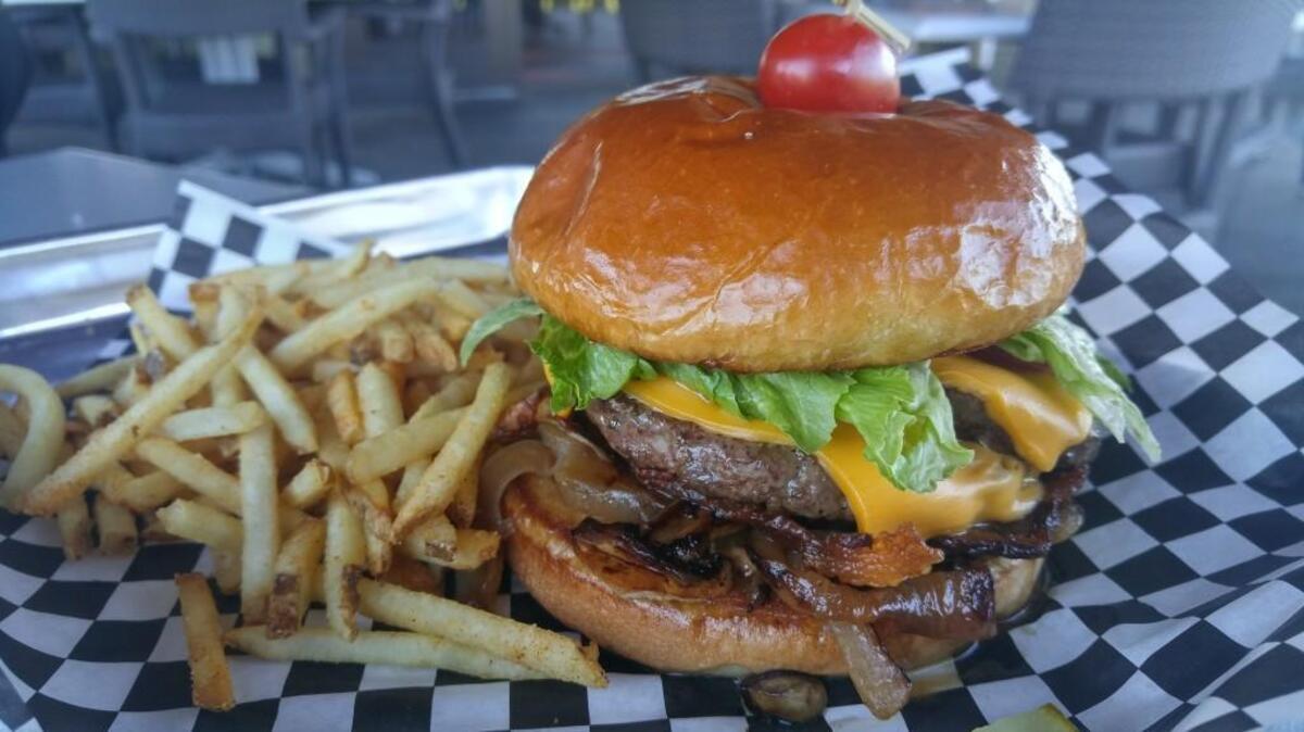 The All-in-One burger at Urban Elk includes double layers of patties and American cheese, with leaf lettuce, a slice of tomato, grilled onions and mushrooms and bacon.