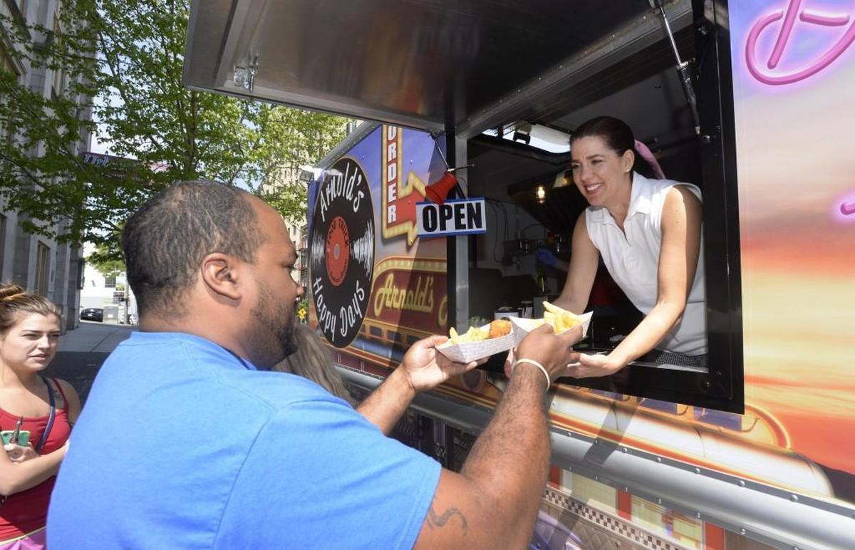 Donna Gross, co-owner of Arnold’s Happy Days food truck, hands R.C. Campbell his order.