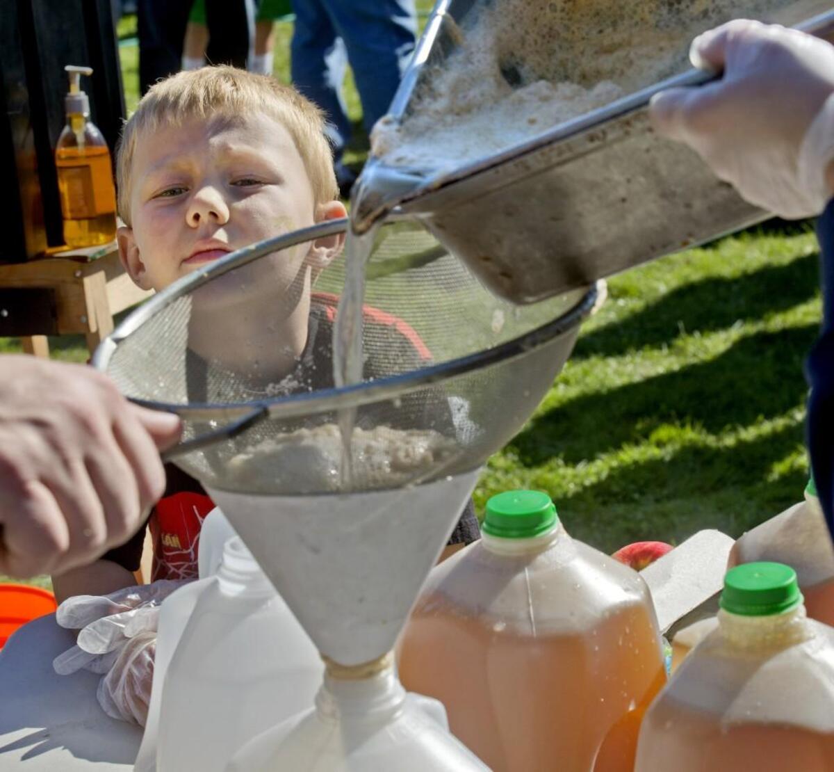 Four-year-old Mikey Oslan of Kent watches the filtering of the final product at the annual Steilacoom Apple Squeeze, October 6, 2013. Saturday’s Apple Squeeze marks the 48th annual interaction of the event.