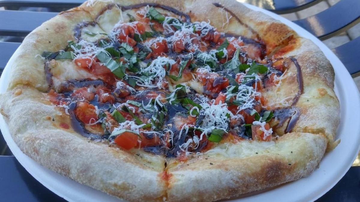 The Margherita pizza from Farrelli’s mobile oven is topped with fresh basil and tomatoes and a squeeze of balsamic syrup.
