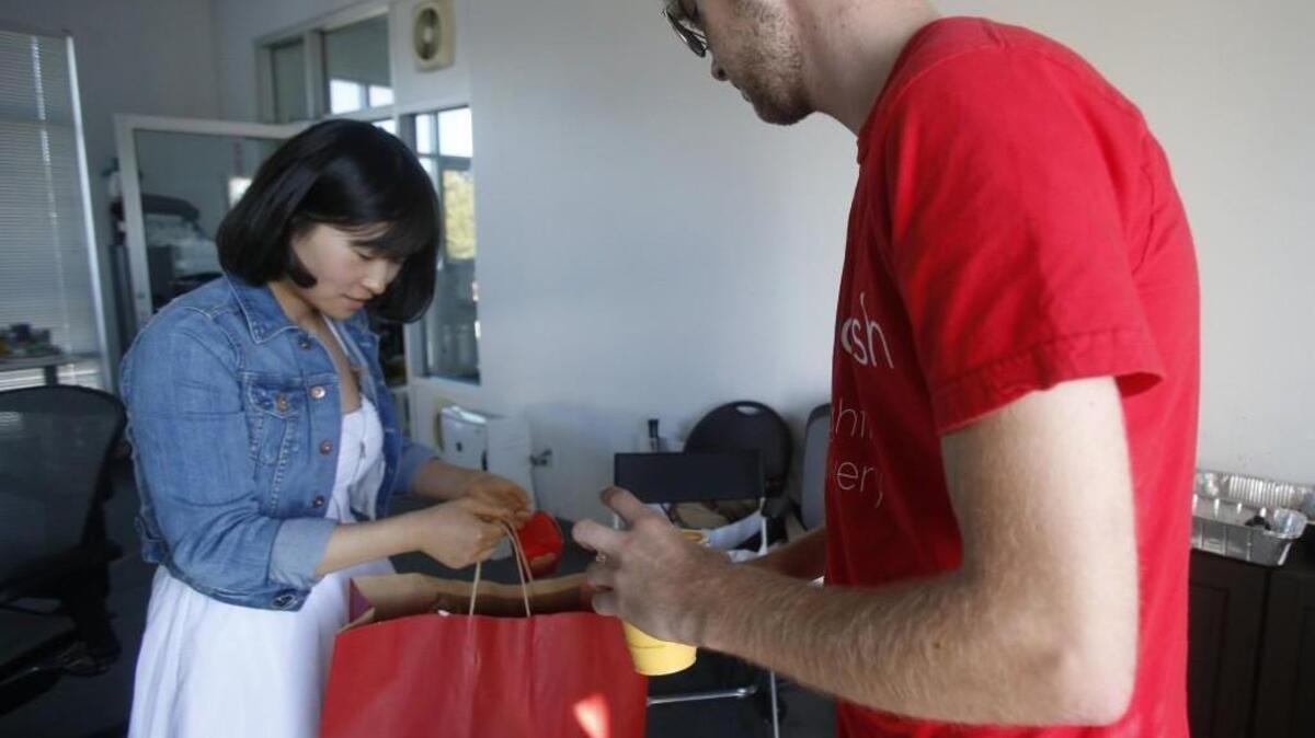DoorDash driver Jake Vertin, right, drops off a Curry Up Now order to Chong Zhang, August 21, 2013, in Palo Alto, California.