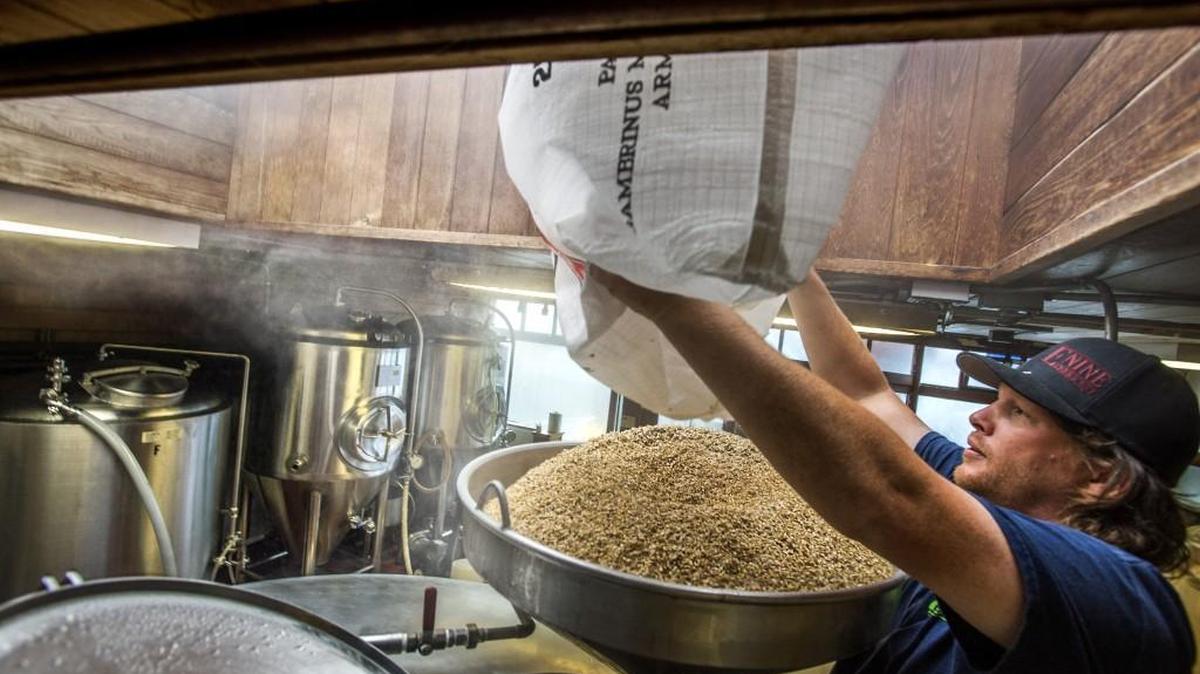Head brewer Shane Johns pours a bag of malted barley into a mash tun full of hot water at the Engine House Number 9 brewery.