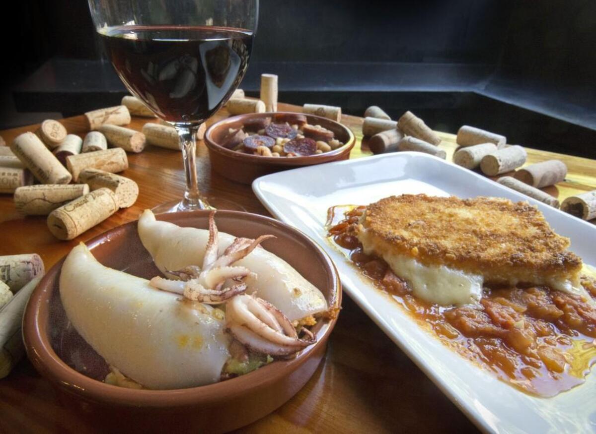Chorizo stuffed calamariat, left, fried mahon cheese with tomato sauce, right, and white beans with chorizo, back center, at El Tufo in Tacoma on Thursday, May 14, 2015. A spanish red wine joins the dishes.