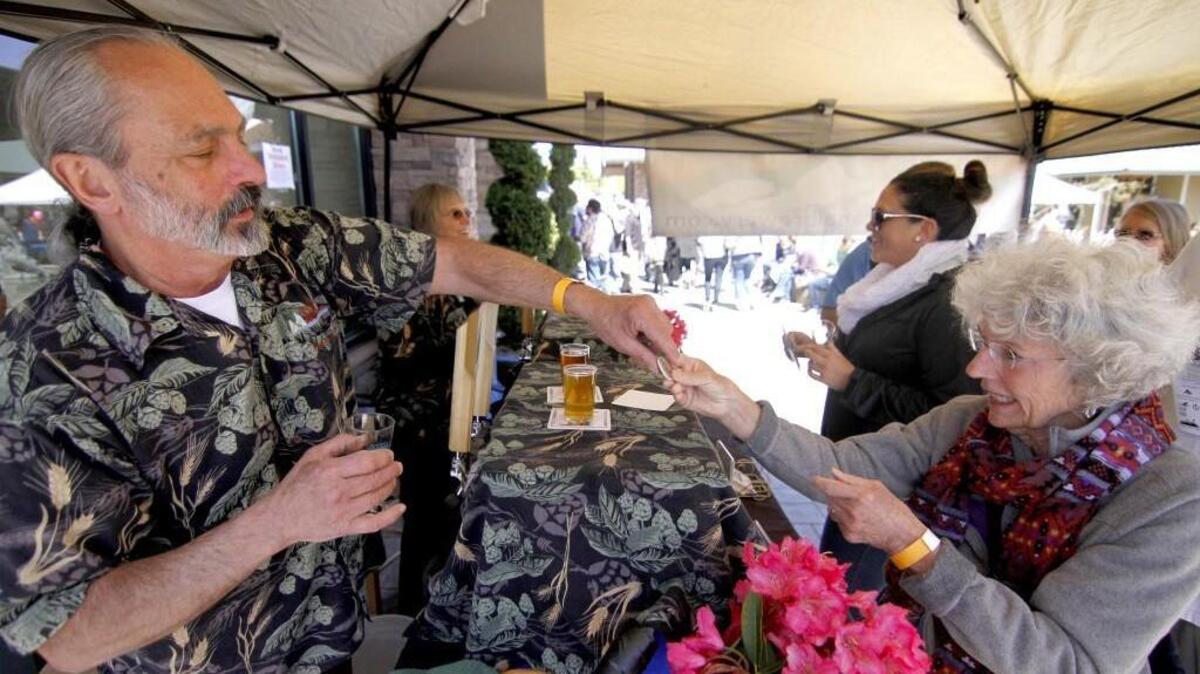 Don Wyatt, co-owner with his wife Chris, of their business, Hood Canal Brewery in Kingston, helps Gig Harbor customer Helen Arnold with a sample of their beer at the 2014 Gig Harbor Beer Festival.