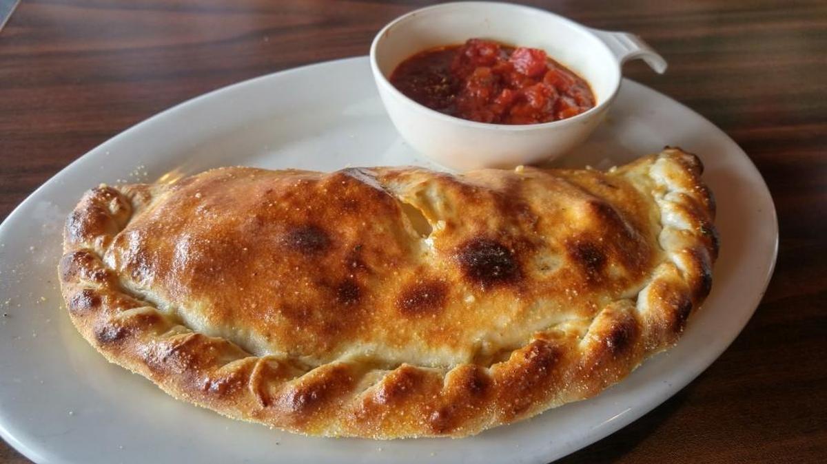 A calzone at Louie G’s Pizza comes filled with a tidy stack of five kinds of meat and mozzarella cheese.