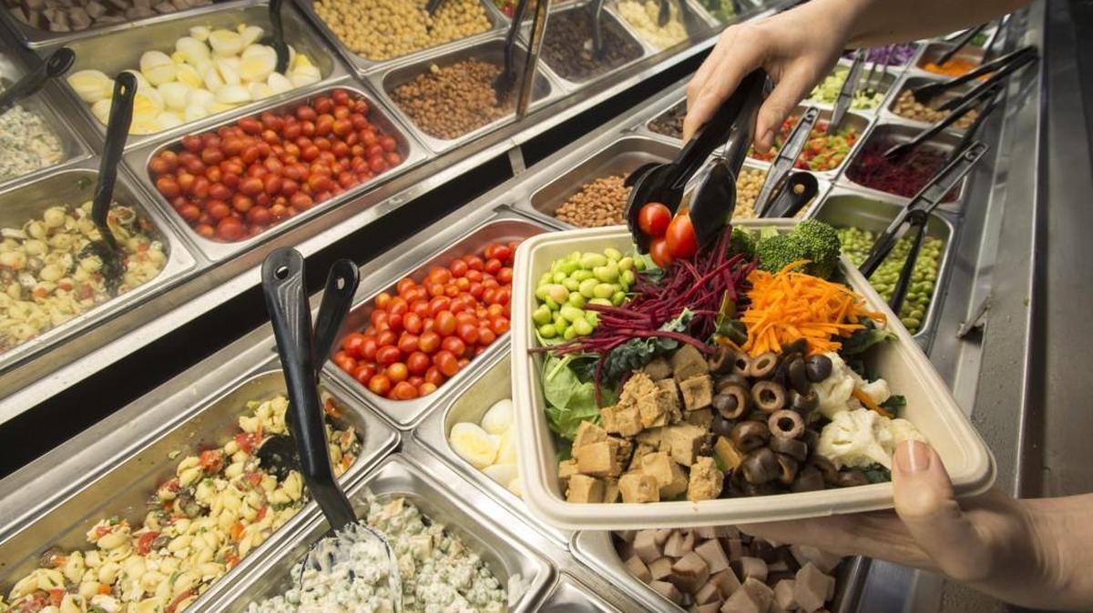 Some of the fresh, organic ingredients available at the salad bar at Marlene’s Natural Foods Market in Tacoma. Besides the fresh vegetables being loaded on this customer’s plate, there are prepared salads such as pea and cheese and Greek, top left.