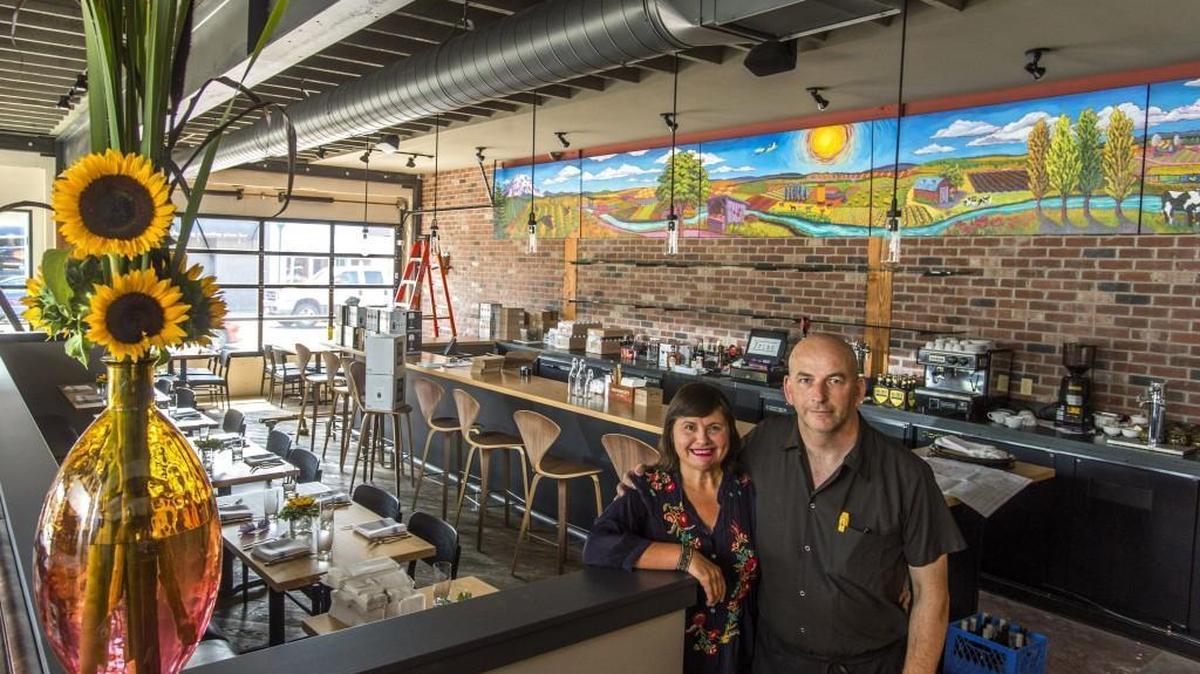 
Jacqueline Plattner and Charlie McManus in the main dining room of the new location of their restaurant Primo Grill. The room features a mural "Puyallup River Valley" by Tacoma Community College Fine Arts students and instructors, and garage-style doors that can be opened in good weather. 
