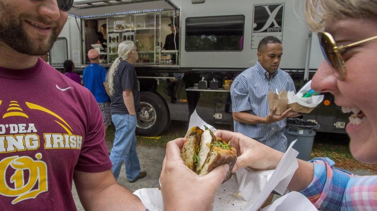 Chuck Maul and Holly Millie tear into a chicken sandwich from Mobile Food Command Center at the 2014 Food Truck Fest in Tacoma's Wright Park.
