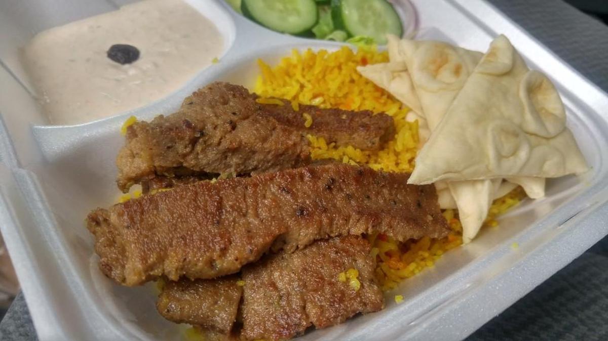 A gyro platter from Infinium Stop comes with sliced gyro meat, rice, pita, salad and sauce.