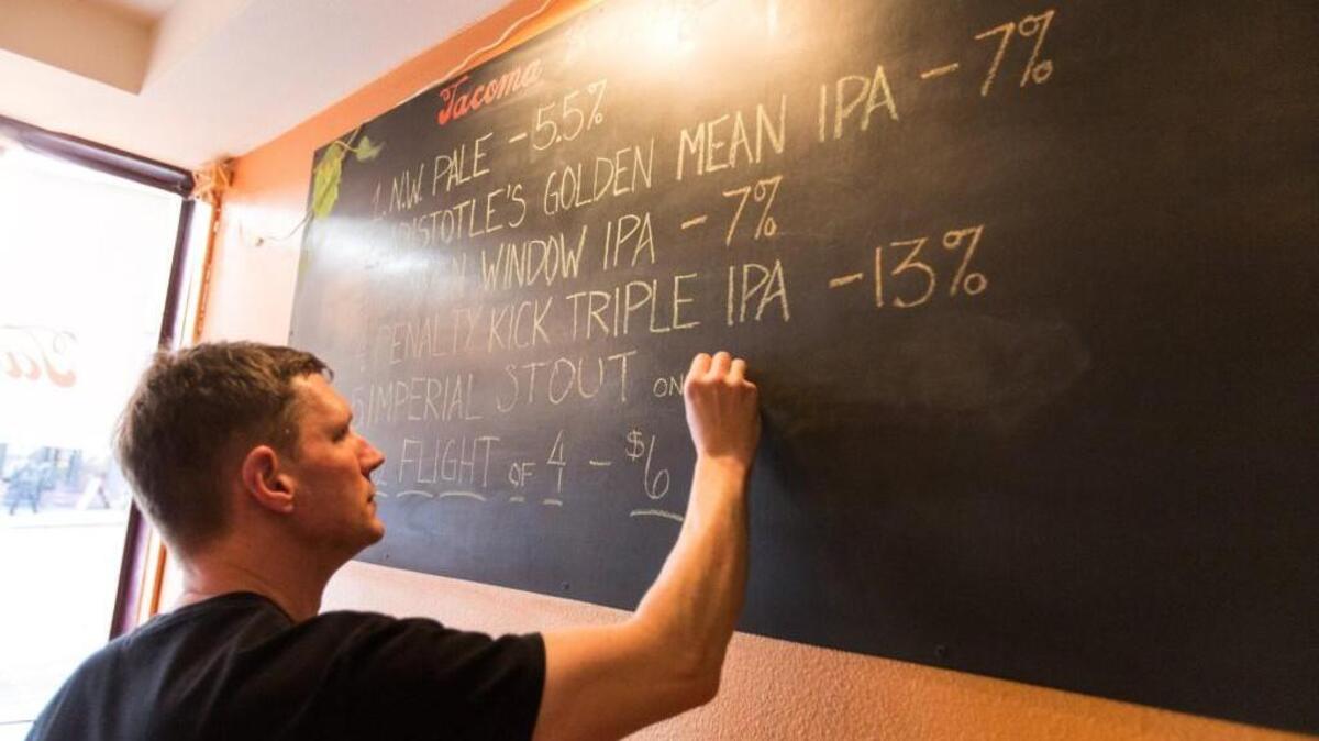 Morgan Alexander, owner of the Tacoma Brewing Company, makes edits to the day's selection of beer at his former location in the St. Helens neighborhood. The Tacoma brewery just moved closer to the historic Brewery District.