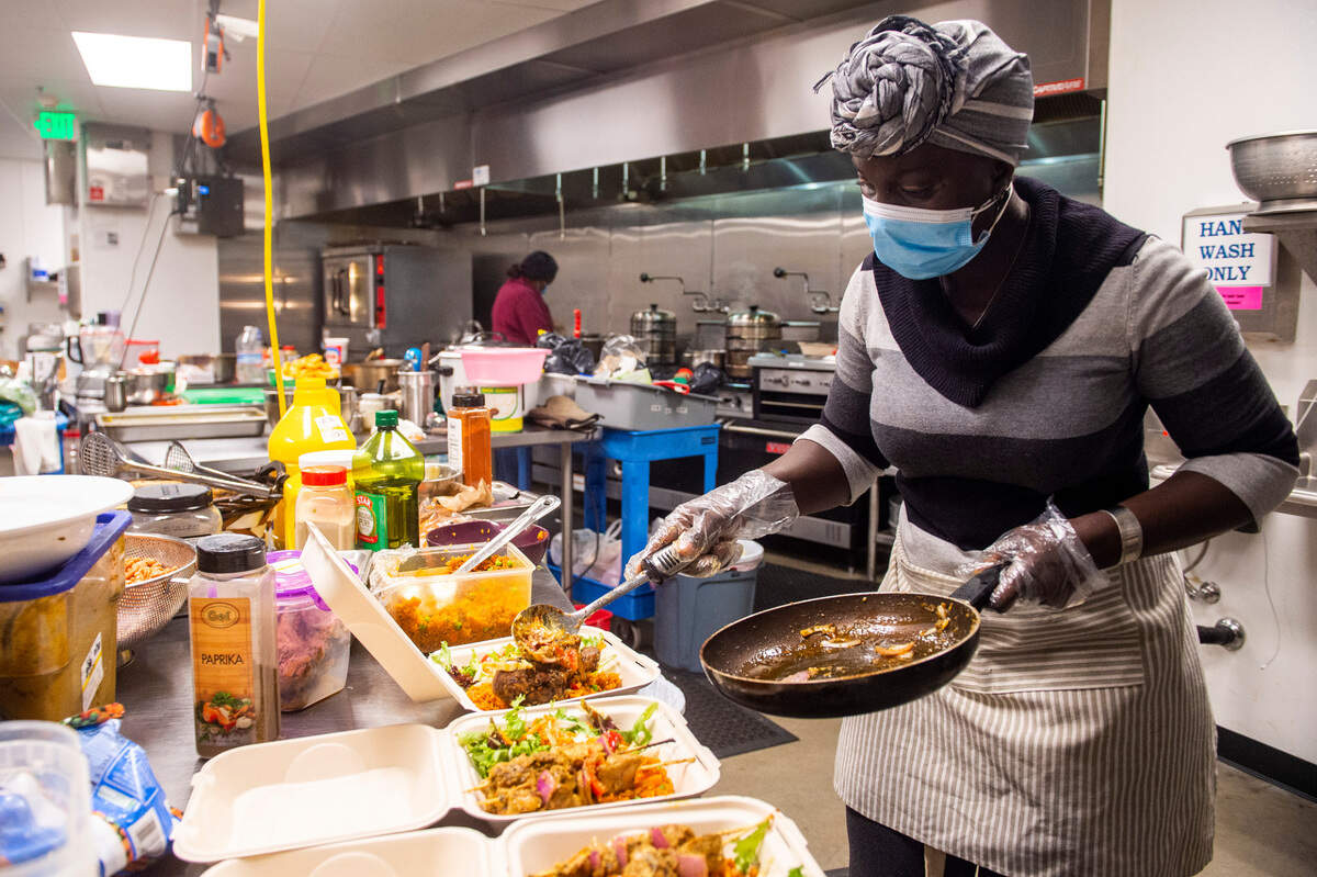 Adama Jammeh of Afella Jollof Catering prepares a pickup order of Senagalese and Gambian dishes on Nov. 18 at Spice Bridge, a global food hall in Tukwila, Washington.