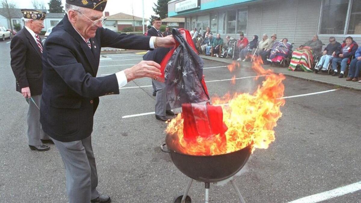 A fuel-oil soaked American flag is added to a bonfire by Lawrence Peterson during a flag disposal ceremony outside the Adult Day Health Center in Tacoma