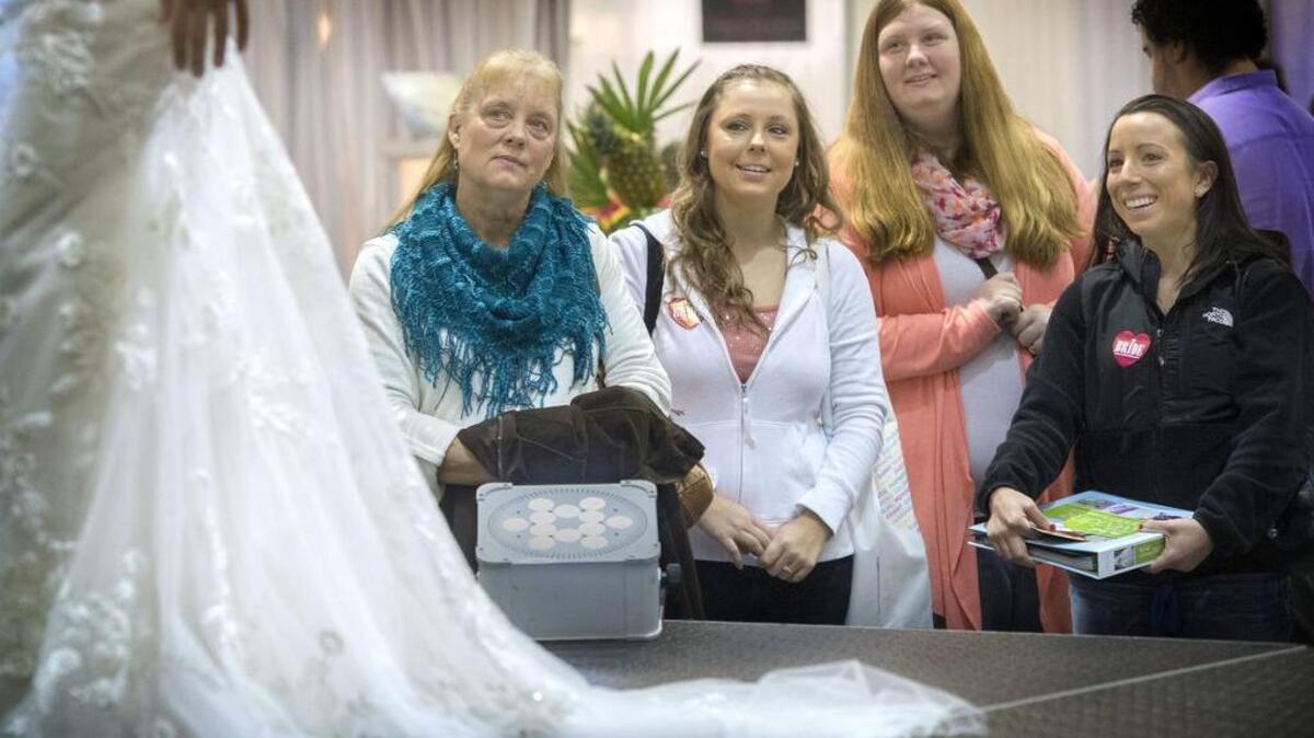 Susie Hamilton, mom, looks at a wedding dress with her daughter, Kalessa, second from left, for her October wedding at the Tacoma Wedding Expo in 2015.