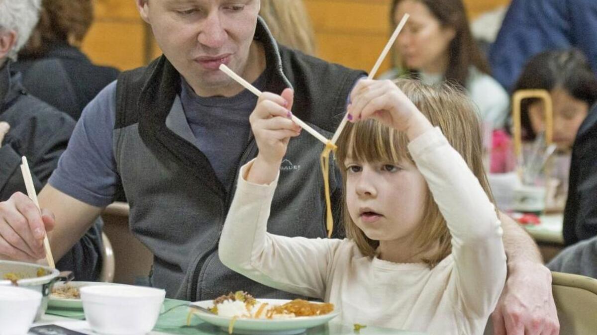Gary Turner helps his five-year-old daughter Grace Turner to use chopsticks for the first time at Tacoma Buddhist Temple’s 50th annual Sukiyaki Dinner fundraiser in 2012.