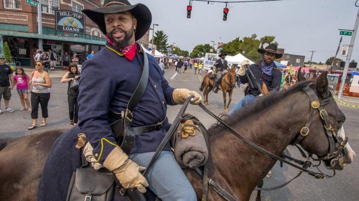 Trooper Leonard Howze Jr. and two others from the Ninth and Tenth Cavalry Buffalo Soldiers of Seattle Reenactment Organization ride their horses at the Hilltop Street Fair held on Martin Luther King Jr. Way in Tacoma, August 22, 2015.  The event included performance stages, booths, car and art exhibitions, booths, food, and kid-friendly fun.