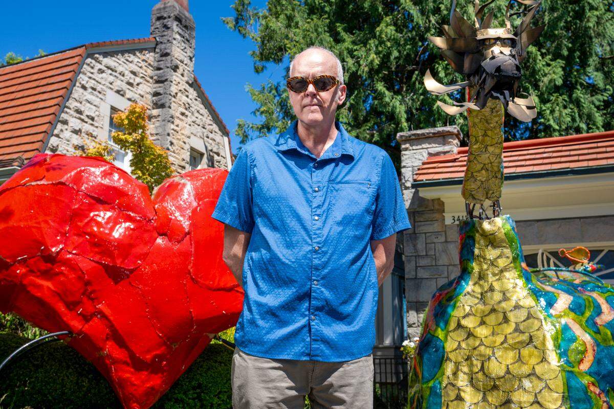 Steve LaBerge stands between two of his creations, The Heart, left, created for The Tacoma Refugee Choir, and The Dragon, a fire-breathing fiberglass vehicle, which will make its annual appearance at the Tacoma Porchfest parade. Shown in his driveway on Monday, July 7, 2025, in Tacoma.