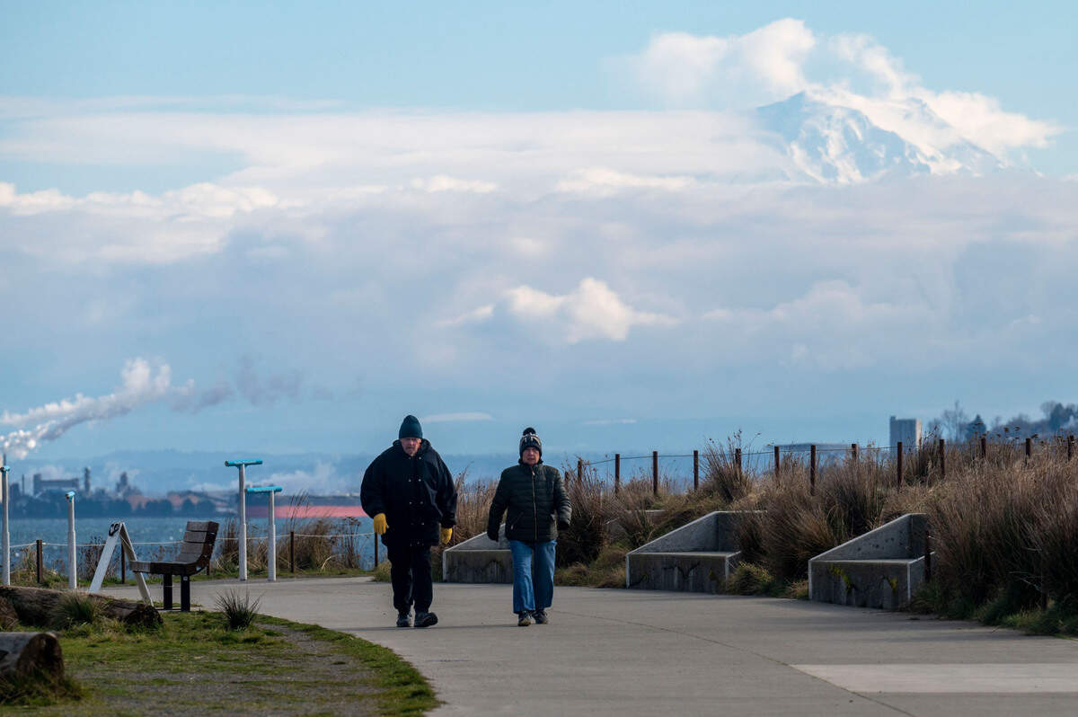 Mount Rainier peaks through the clouds while high winds and cold temperatures made for uncomfortable walking conditions at Dune Peninsula in Ruston, Wash., on Tuesday, Feb. 22, 2022.