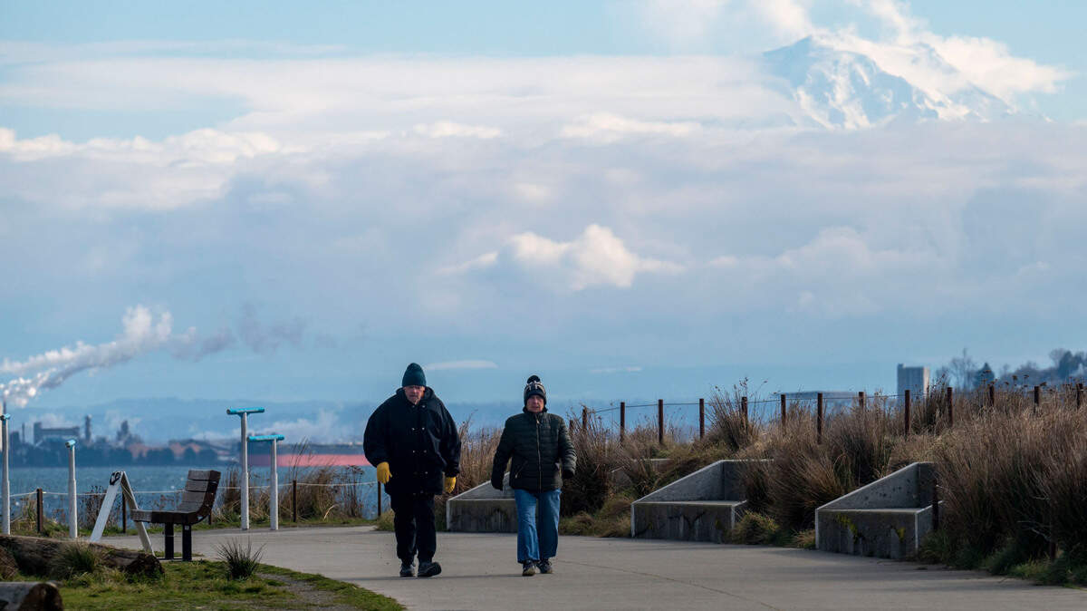 Mount Rainier peeks through the clouds while high winds and cold temperatures made for uncomfortable walking conditions at Dune Peninsula in Ruston, Wash., on Tuesday, Feb. 22, 2022.