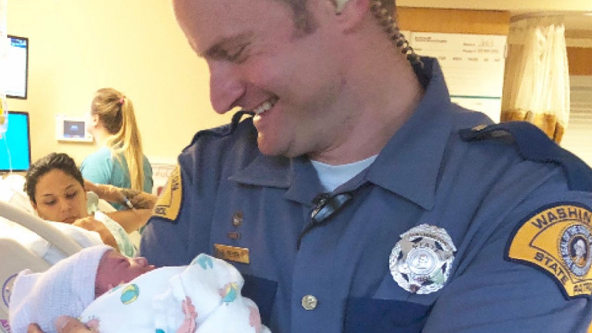 Washington State Patrol trooper Rob Reyer holds a newborn girl Thursday. The baby was born in the southbound lanes of state Route 509 at Portland Avenue in Tacoma. Trooper Pedro Bidot delivered the baby.
