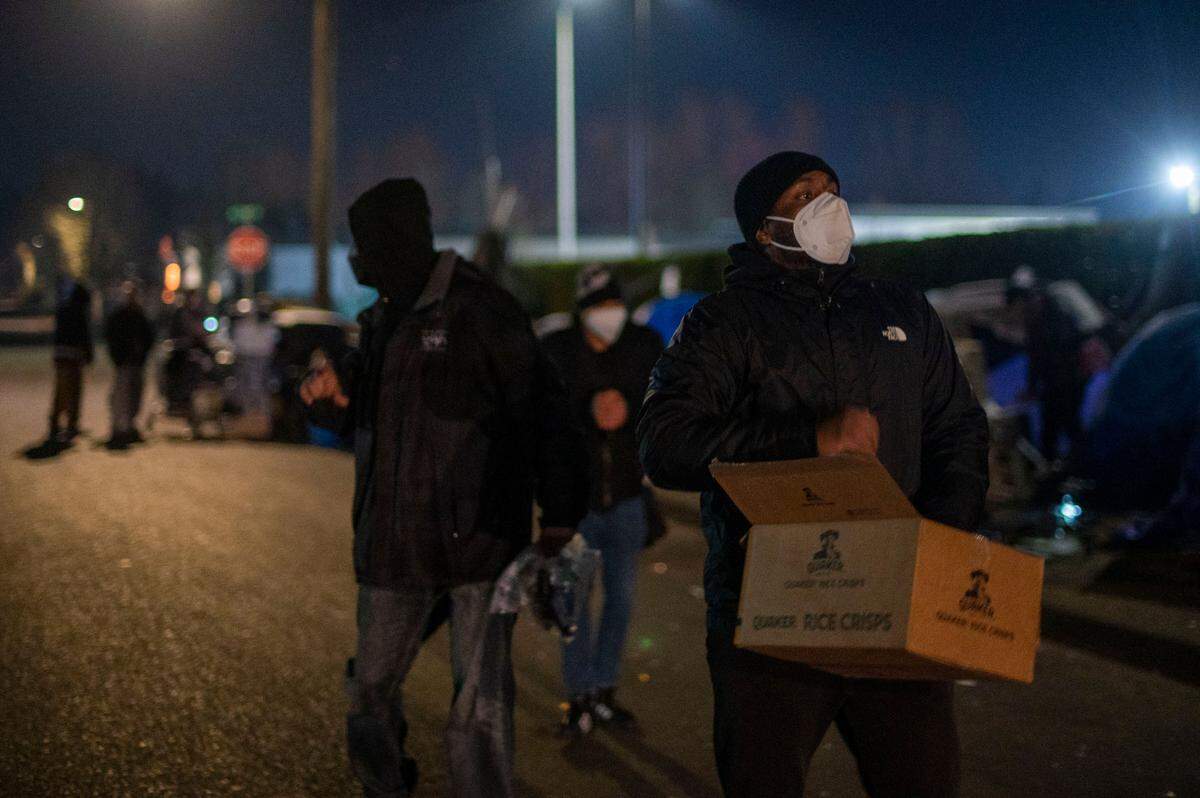 Volunteers hand out food and supplies to people living unhoused along East I Street in Tacoma, Wash., on Thursday, Jan. 27, 2022.