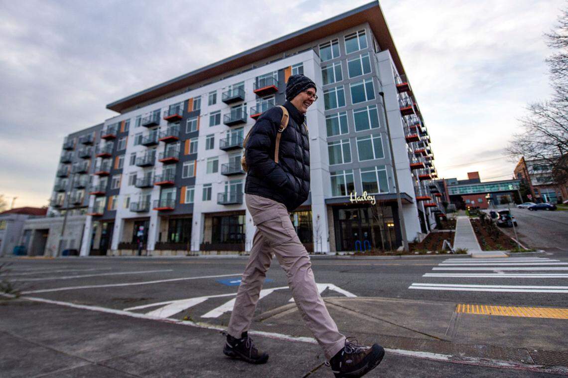 A person walks down Tacoma Avenue past The Hailey Apartments on Feb. 9, 2022, in Tacoma. The project launched in 2017 to much fanfare about converting a city parking lot next to the downtown public library to much-needed housing with affordable units included. The move to a 8-year multifamily tax exemption to allow for all market-rate units, was made to qualify for a new construction loan and required City Council approval, which delayed progress.