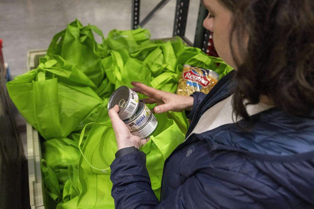 Claire Aijian, development director with Emergency Food Network, shows some foods included in a distribution bag, including items like canned goods, pasta and peanut butter, on Tuesday, Oct. 28, 2025, in Tacoma, Wash.
