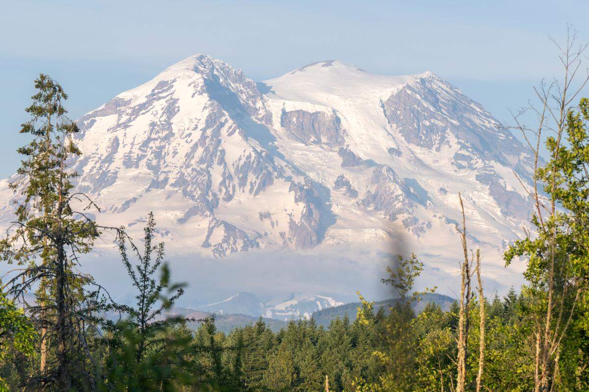 The light from a setting sun highlights Mount Rainier, visible from a road outside of Mount Rainier National Park, on Friday, June 6, 2025.