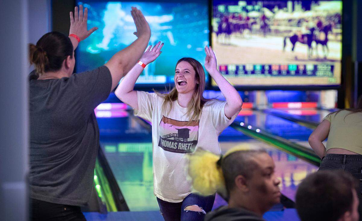 Annie Heilman of Puyallup celebrates with her mom, Beth Heilman, after making a strike while bowling during the family & friends soft opening of the Round 1 entertainment venue at the South Hill Mall in Puyallup, Washington on Friday, Aug. 12, 2022.