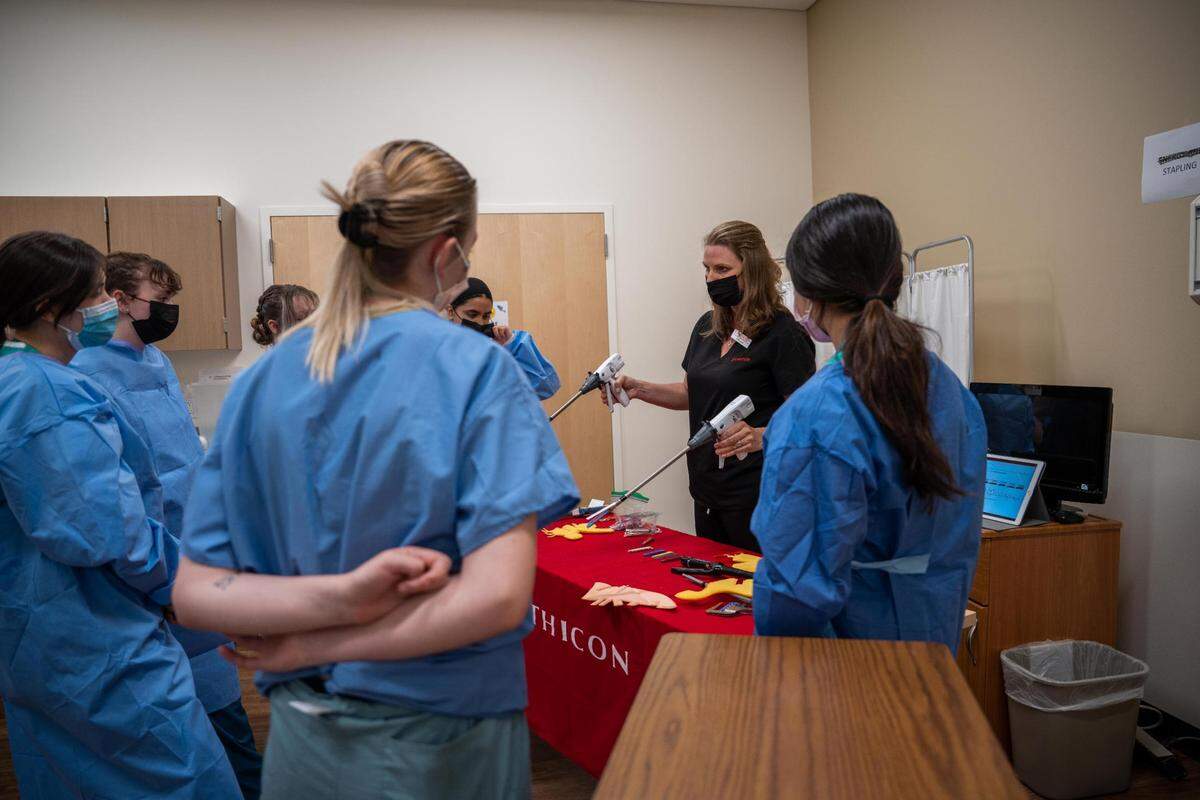 Deb Linne who is an account executive shows the attendees of MultiCare’s M.A.S.H. camp how to use staplers at her station on the third day of their camp.