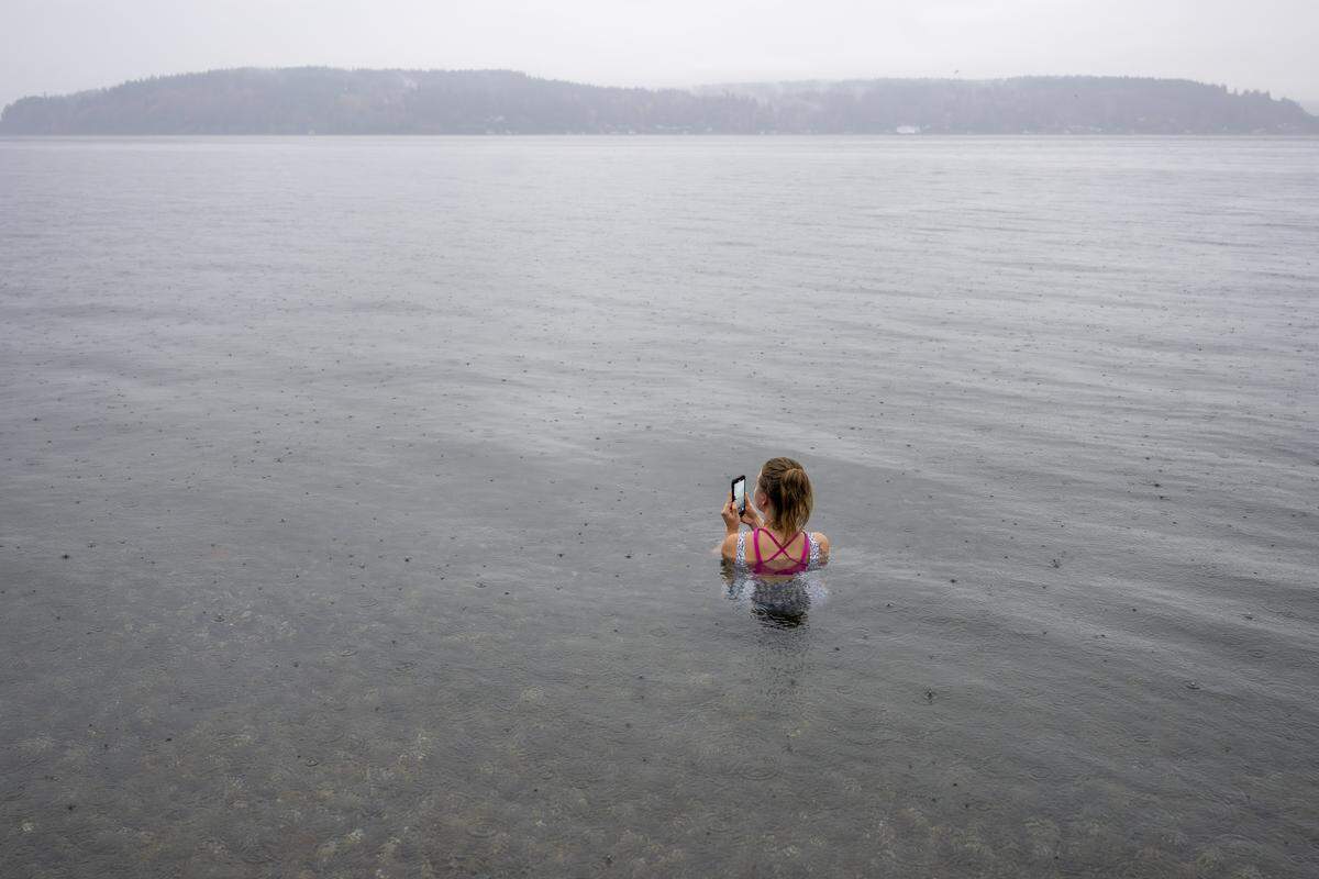 Amanda Ryken plunges into the Puget Sound while recording the misty surroundings at Owen Beach on Friday, Oct. 31, 2025, in Tacoma, Wash. Ryken plunged between two hot sessions in the Svette Sauna located in the parking lot of Owen Beach at Point Defiance Park.