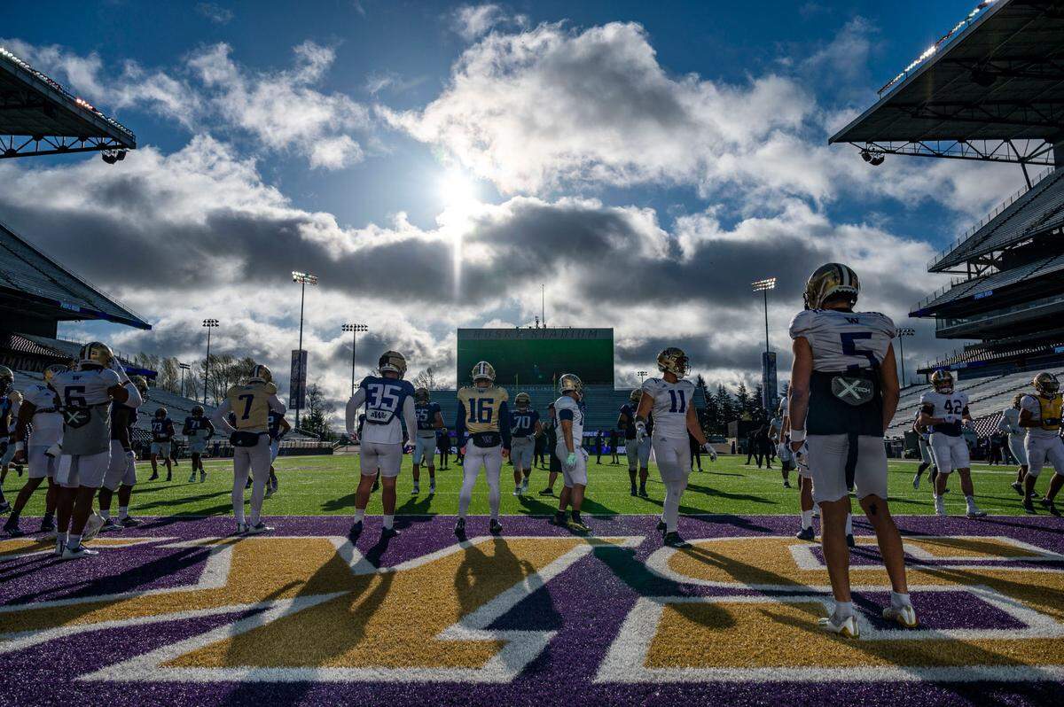 Washington players warm up at the beginning of spring practice on Friday, April 8, 2022, at Husky Stadium in Seattle.