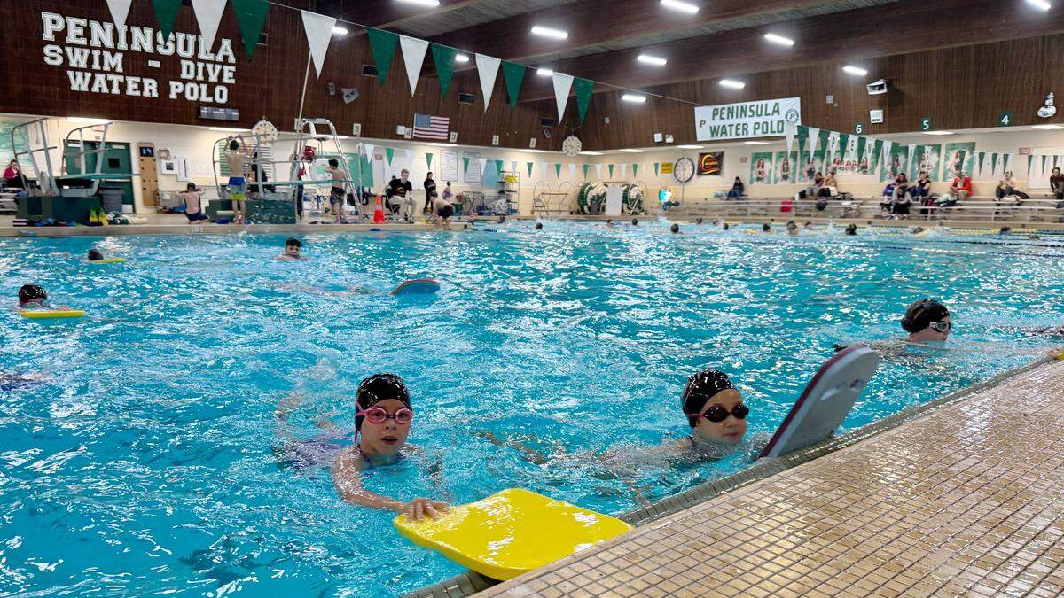 Harbor Aquatics Club swimmers practice with kickboards in the pool at Peninsula High School. The pool is shaped like an L, allowing less advanced swimmers to practice separately from swimmers in the regular six lanes.
