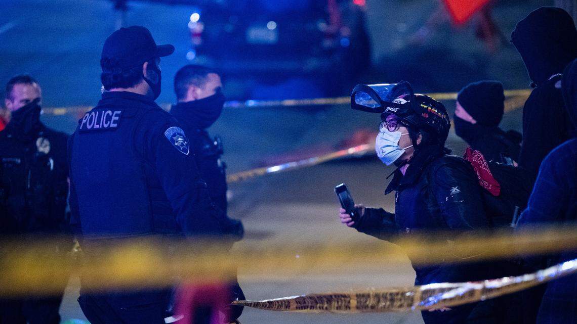 Protesters argue with police at South 9th Street and Pacific Avenue where earlier a Tacoma police car ran through a crowd of people at the scene of cars doing burnouts in Tacoma, Wash., on Saturday, Jan. 23, 2021.