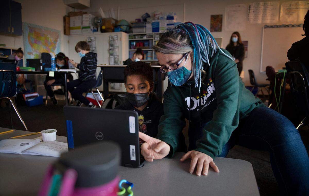 DeLong Elementary teacher Jennifer Fagan’s helps fifth grader Elijah Solai in her combined fourth- and fifth-grade class at DeLong Elementary School in Tacoma, Washington, on Wednesday, Jan. 19, 2022.