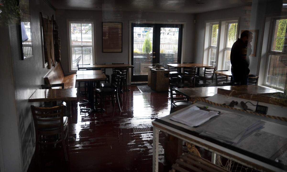 Justin Coronado of Gig Harbor gives an update on the flooding at Netshed No. 9 restaurant that was inundated by high-tide floodwaters at Skansie Brothers Park and Netshed along the waterfront in Gig Harbor, Washington, on Tuesday, Dec. 27, 2022.