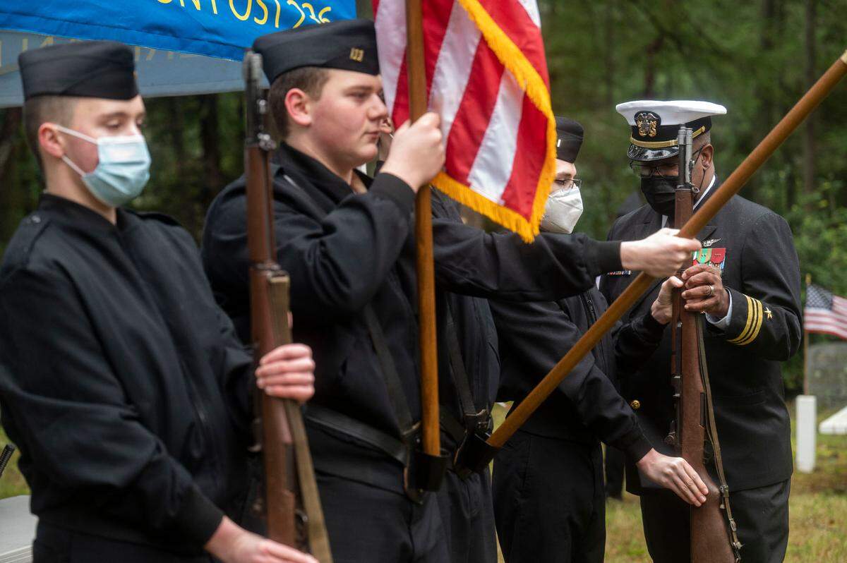 Lieutenant Commander Darrell Hood helps cadet ensign Tate Kamasz, a sophomore at Gig Harbor High School, with his rifle positioning as part of the Peninsula Navy National Defense Cadet Corps color guard prior to the start of a Wreaths Across America ceremony at Artondale Cemetery in Gig Harbor, Wash., on Saturday, Dec. 18, 2021.