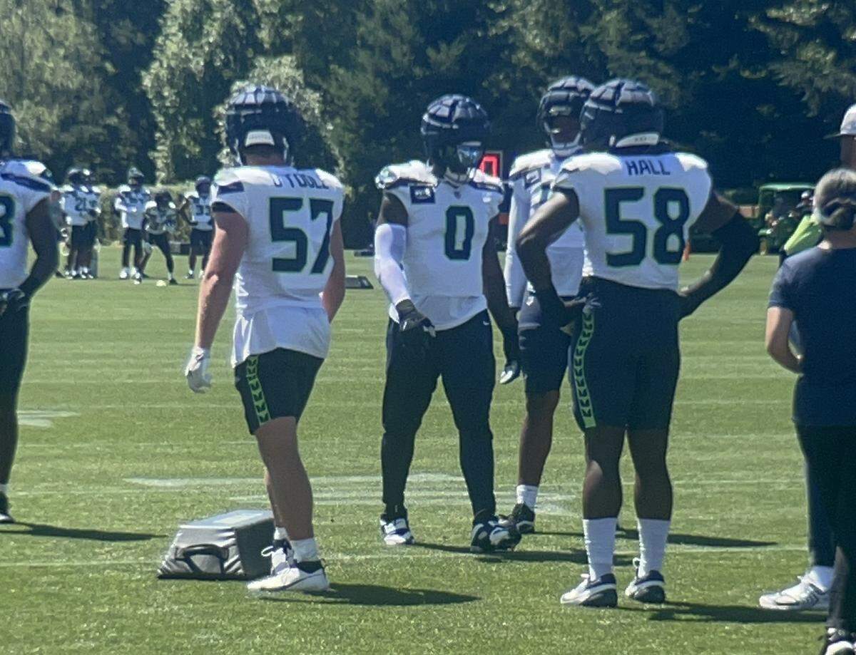 Defensive end DeMarcus Lawrence (0) walks between teammates Connor O’Toole (57) and Derick Hall (58) during the sixth practice of Seattle Seahawks NFL training camp Tuesday, July 29, 2025, at the Virginia Mason Athletic Center in Renton.