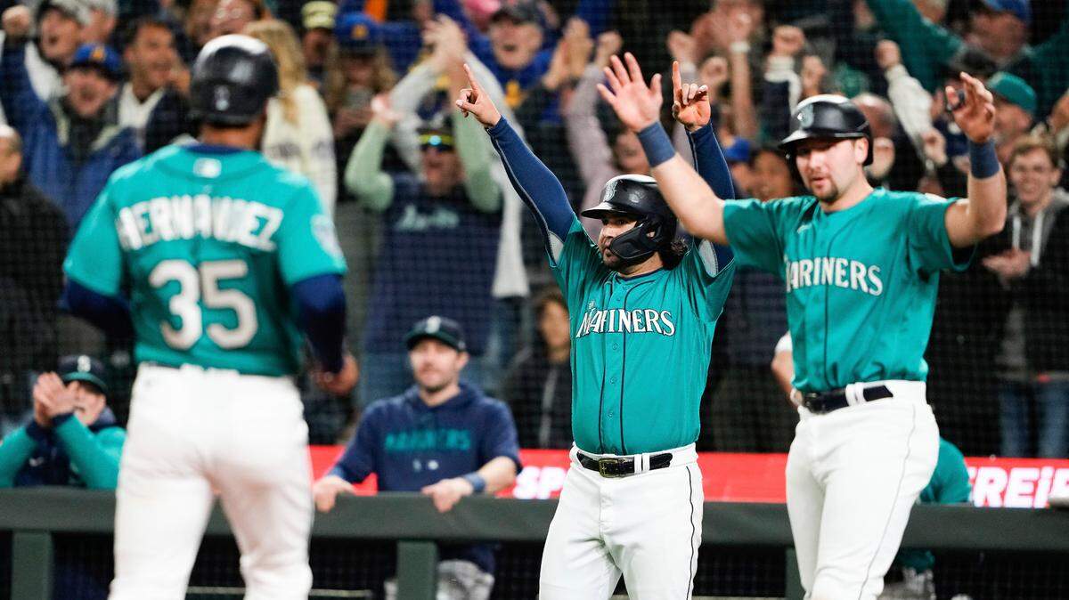 Seattle Mariners’ Teoscar Hernandez (35) is greeted by Eugenio Suarez, center, and Cal Raleigh, right, after all three scored on a double by J.P. Crawford against the Houston Astros during the eighth inning of a baseball game Saturday, May 6, 2023, in Seattle. (AP Photo/Lindsey Wasson)