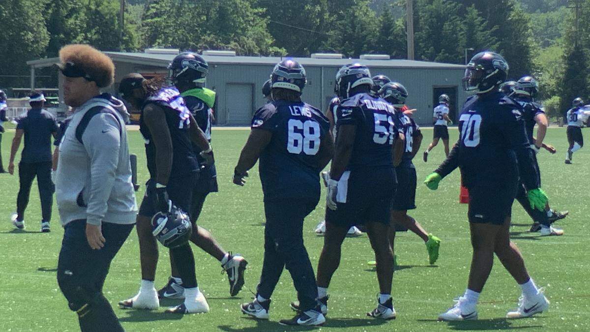 Rookie center Olu Oluwatimi (51) with starting left guard Damien Lewis (68) and rookie guard Anthony Bradford (70) flanking him between drills at the Seahawks’ third practice of organized team activities (OTAs) May 25, 2023, at team headquarters in Renton. Offensive line coach Andy Dickerson is in grey at the far left.